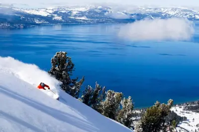 a person skiing down a snow covered slope next to the water at Lake Views in 3bdr Family Home w/ Hottub in South Lake Tahoe