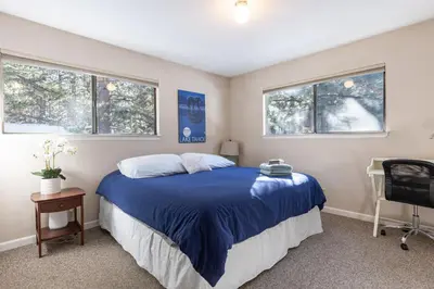 a bedroom with a blue bed and two windows at Lake Views in 3bdr Family Home w/ Hottub in South Lake Tahoe