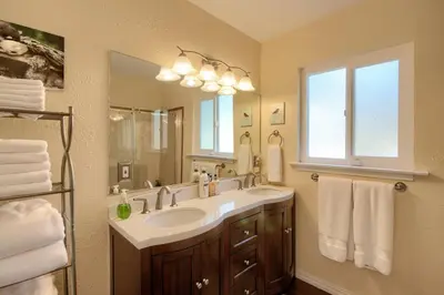 a bathroom with a sink and a large mirror at Yosemite Corner w NEW game room/Hot Tub/EV more in Oakhurst