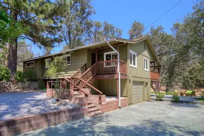 a small green house with a porch and stairs at Yosemite Corner w NEW game room/Hot Tub/EV more in Oakhurst