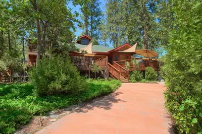 a large log house with a walkway in front of it at Willow Cove Lodge- 5 bedrooms with a hot tub in Bass Lake