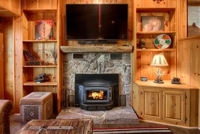 a living room with a fireplace and a flat screen tv at Willow Cove Lodge- 5 bedrooms with a hot tub in Bass Lake