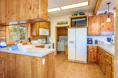 a kitchen with wooden cabinets and a white refrigerator at Bass Lake Log Home - Dog Friendly in Bass Lake