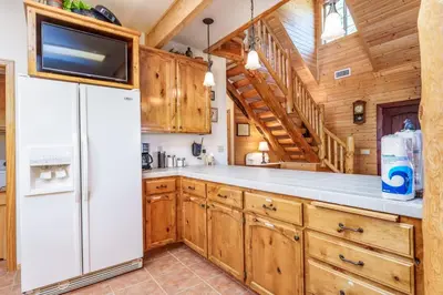 a kitchen with wooden cabinets and a white refrigerator at Bass Lake Log Home - Dog Friendly in Bass Lake