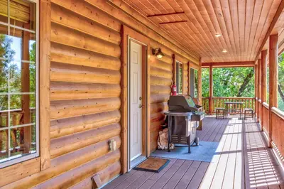 a front porch of a wooden cabin with a door at Bass Lake Log Home - Dog Friendly in Bass Lake