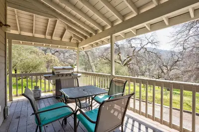 a porch with chairs and a table and a grill at Selah Cabin- Dog Friendly/BBQ/Level 2 EV Charger in Oakhurst