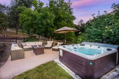 a hot tub in a yard with a table and chairs at Emerald Escape 50 Acres w/Hot Tub, Game Room in Oakhurst