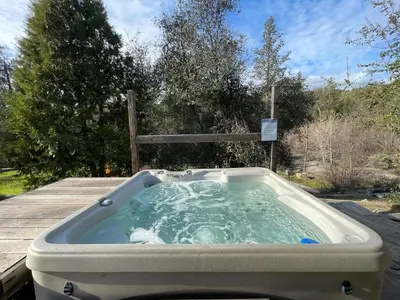 a jacuzzi tub sitting on top of a deck at River View Retreat Sleeps 16/ hot tub/basketball court in Oakhurst