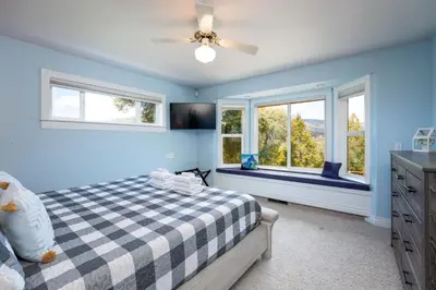 a blue bedroom with a bed and two windows at Yosemite Adventure House with Pool-hot tub-game room in Oakhurst