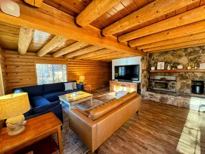 a living room with a couch and a fireplace at Log Cabin w/ pool, spa, game room, sleeps 20 in Coarsegold