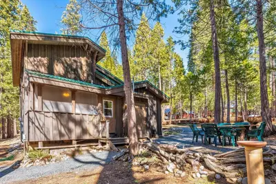 a cabin in the woods with a table and chairs at Place to Call Home - Cabin INSIDE Yosemite - Dog Friendly in South Wawona