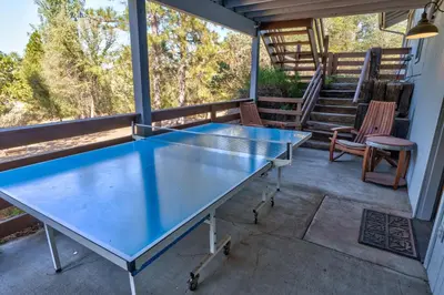 a ping pong table on the back porch of a house at Stimboli Lodge- Sleeps 16 with tons of games and fun in Oakhurst