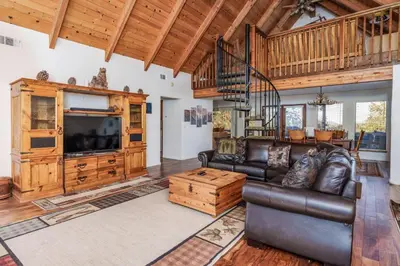 a living room with a leather couch and a television at Stimboli Lodge- Sleeps 16 with tons of games and fun in Oakhurst