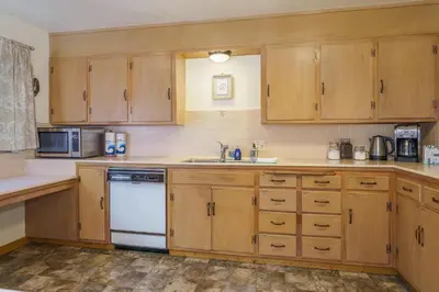 a kitchen with wooden cabinets and a white dishwasher at Peace of Mine - Cabin inside Yosemite - Dog Friendly in South Wawona