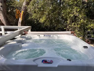 a jacuzzi tub in a backyard with trees at Doe Cabin Hot Tub/Playground/Game Room and more in Oakhurst