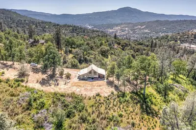 an aerial view of a house on top of a hill at Hilltop Haven- Bright and Modern Cabin w/ hot tub and stunning views in Oakhurst