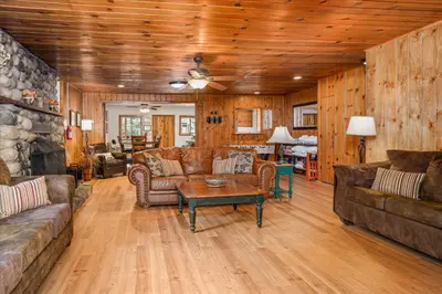 a living room with leather furniture and a stone wall at Cub House- Remodeled cabin INSIDE Yosemite with new hot tub and more in North Wawona