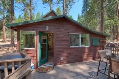 a cabin in the woods with a deck at Beetlebark Bungalow- Inside Yosemite w/ hot tub EV charging cable in North Wawona