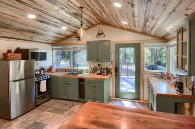 a kitchen with green cabinets and a wooden ceiling at Beetlebark Bungalow- Inside Yosemite w/ hot tub EV charging cable in North Wawona
