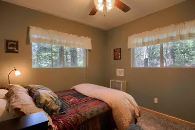 a bedroom with a bed with a fan and two windows at Hibernation Hideaway- Inside Yosemite- Dog Friendly in South Wawona