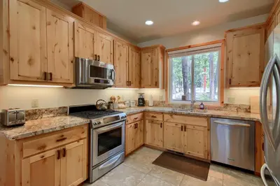 a kitchen with wooden cabinets and stainless steel appliances at Rivercrest Lodge with Hot Tub-Pool Table-Firepit in North Wawona