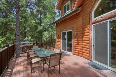 a wooden deck with a table and chairs on it at Rivercrest Lodge with Hot Tub-Pool Table-Firepit in North Wawona