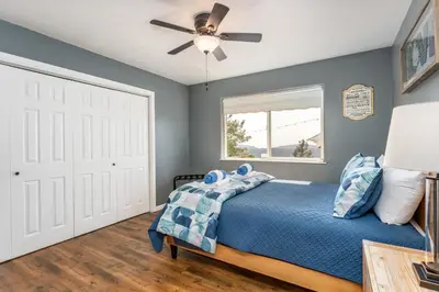 a bedroom with a blue bed and a ceiling fan at Skyline Lodge- amazing views w/spa/game room in Oakhurst