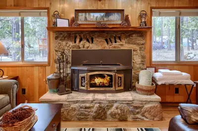 a fireplace in a living room with a stone wall at Acorn Alley- inside Yosemite w/spa/firepit/sauna/EV in North Wawona