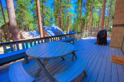 a picnic table and chairs on a deck with trees at Foothill Folly home in Zephyr Cove