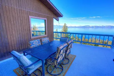 a blue table and chairs on a balcony with a view of the water at Lake View Glen home in Lincoln Park