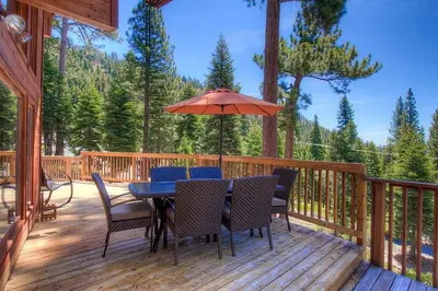 a deck with a table and chairs and an umbrella at The Bass Chalet home in Kings Beach