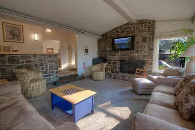 a living room with a couch and a stone fireplace at Cheyenne Chalet home in Round Hill