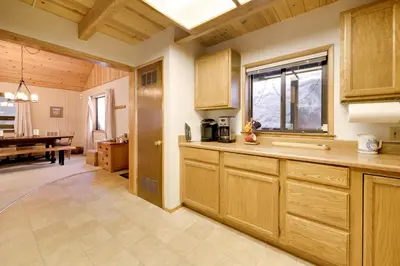 a kitchen with wooden cabinets and a dining room at 6 Mi to Sugar Bowl Resort Soda Springs Cabin! in Soda Springs