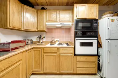 a kitchen with wooden cabinets and a white refrigerator at 6 Mi to Sugar Bowl Resort Soda Springs Cabin! in Soda Springs