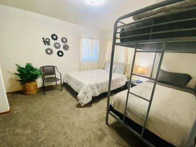 a bedroom with two bunk beds and a chair at Family friendly, 3 bedroom house, with king bed for up to 15 - BBQ - Internet - jet tub in Auburn