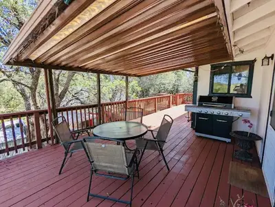 a patio with a table and chairs on a deck at Family friendly, 3 bedroom house, with king bed for up to 15 - BBQ - Internet - jet tub in Auburn