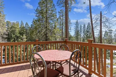 a table and chairs on a deck with trees at Big Trees, Little Cabin in Arnold