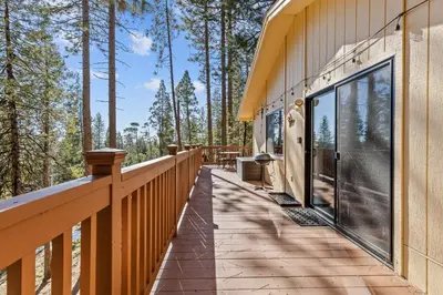 a deck on the side of a house with trees at Big Trees, Little Cabin in Arnold