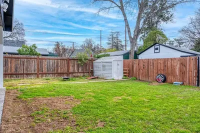 a backyard with a wooden fence and a yard at 4BR Victorian Walk to UC Davis & Shriner Med Cen in Sacramento