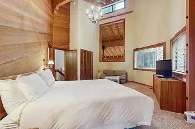a bedroom with a large white bed and a television at North Star Mountain Retreat in Truckee