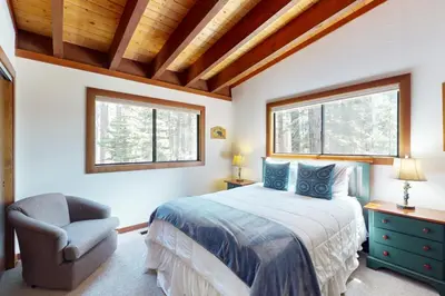 a bedroom with a bed and a chair and windows at Tree-Lined Views #8 in Tahoe City