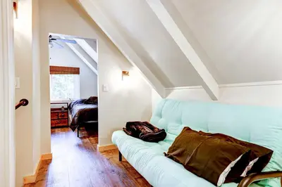 a living room with a blue couch in a attic at Hike, Fish and Explore California Cabin with Deck! in Long Barn