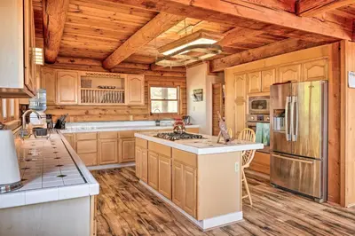 a kitchen with wooden cabinets and a refrigerator at Stunning Log Cabin with Great Views, Firepit, Deck near Twain Hart in Sonora