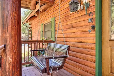a porch swing hanging from the side of a log house at Stunning Log Cabin with Great Views, Firepit, Deck near Twain Hart in Sonora