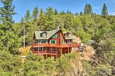 a large wooden house on a hill in the woods at Stunning Log Cabin with Great Views, Firepit, Deck near Twain Hart in Sonora