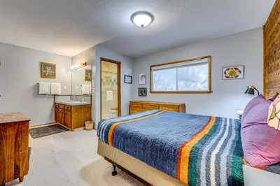 a bedroom with a bed and a bathroom with a sink at The Big White Cottage in Truckee
