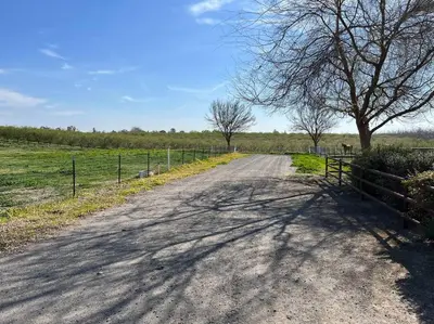 a dirt road with a fence and a tree at Adorable 1 Bedroom with pool, and Horse Arena in Oakdale
