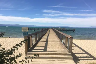 a wooden boardwalk stretches out into the ocean on a beach at Our Happy Place home in South Lake Tahoe