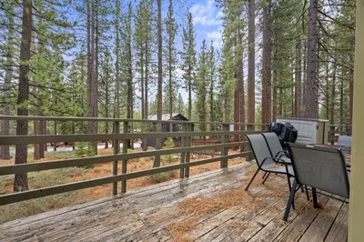 a deck with a chair and a grill and trees at Cozy Cabin home in South Lake Tahoe