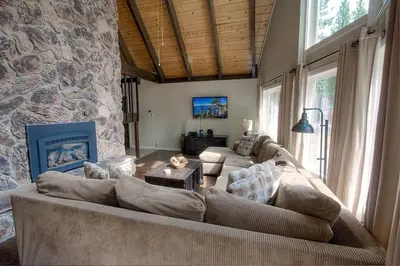 a living room with a couch and a stone wall at Snowshoe Chalet cabin in South Lake Tahoe